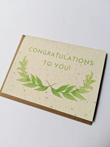 a plantable seed card - the card has a textured look from the seeds imbedded in the paper. There is a leaf drawing on this and it also says "CONGRATULATIONS TO YOU"