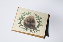 Load image into Gallery viewer, a plantable seed card - the card has a textured look from the seeds imbedded in the paper. There is a drawing of a porcupine surrounded by pine sprigs on this card