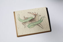 Load image into Gallery viewer, a plantable seed card - the card has a textured look from the seeds imbedded in the paper. There is a deer drawing on this one that says "HAPPY HOLIDAYS" on a green banner going across the deer