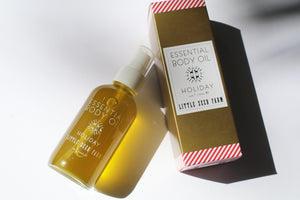a bottle of holiday body oil by Little Seed next to the box it comes with
