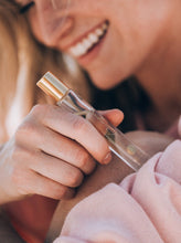 Load image into Gallery viewer, a woman holding a roll on perfume bootle that says "Bungalow" in gold
