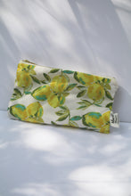Load image into Gallery viewer, a cream colored cosmetic bag with a gold zipper and lemon design