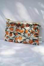 Load image into Gallery viewer, a cream colored cosmetic bag with a gold zipper and orange design
