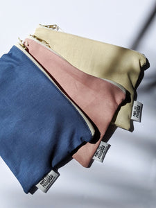 three bags laying on top of each other - one dusty blue, one dusty rose pink, and one natural tan color