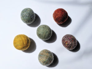5 wool dryer balls that vary in color from maize, to olive green, to red. 