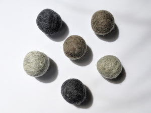 5 wool dryer balls that are gray varying from light gray to dark gray 