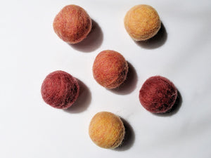 5 wool dryer balls that are warm toned varying from light orange and red to dark orange and red