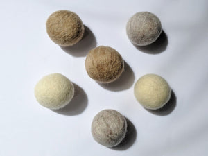 5 wool dryer balls that are neutral colors varying from white to brown 