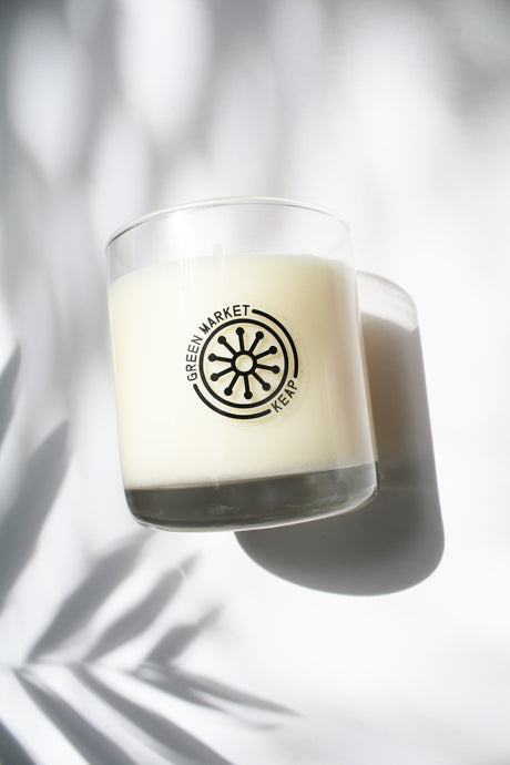 an up close video of a candle - the candle wax is a white color and is inside a clear glass container that doubles as a drinking tumbler once the candle burns out.