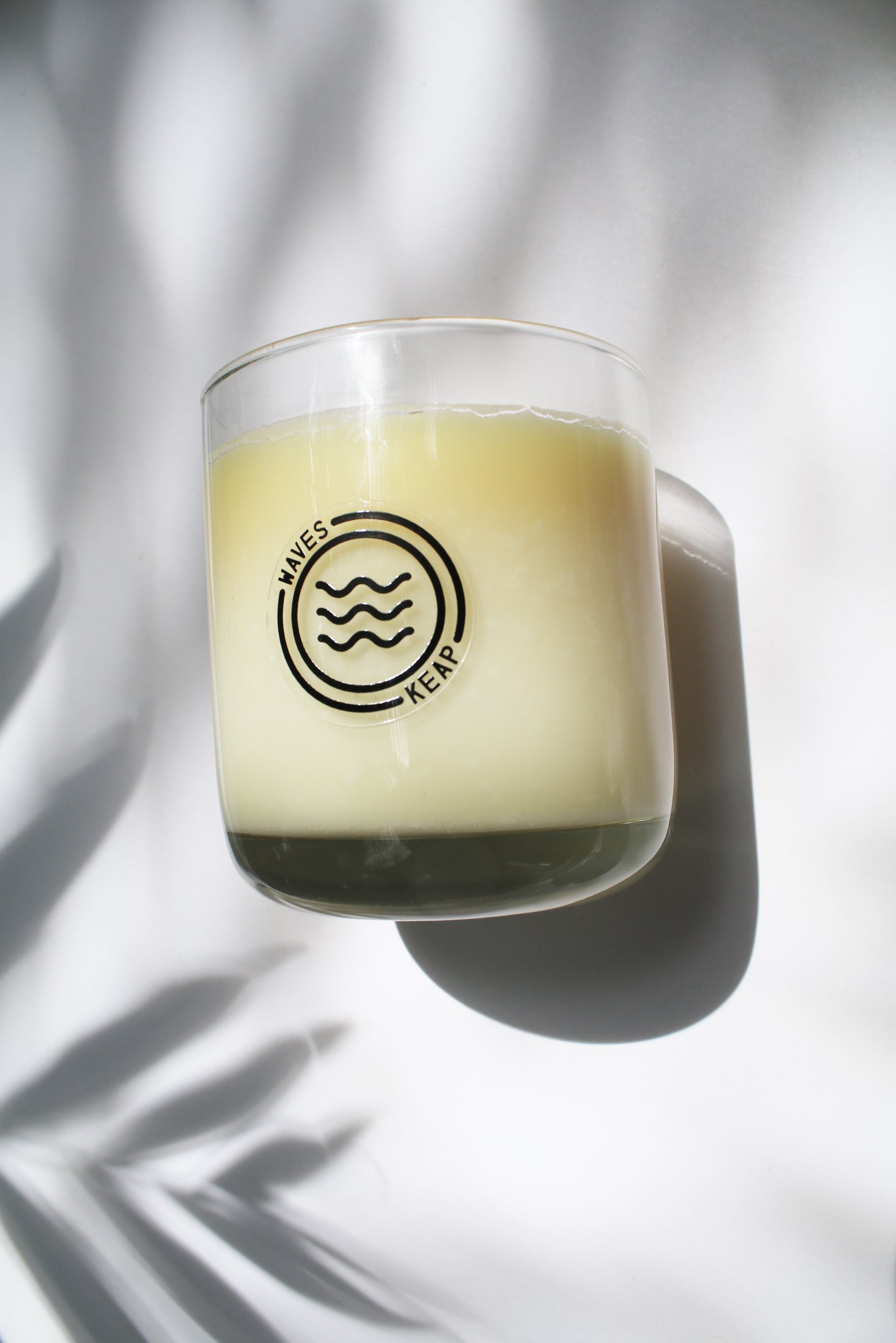 an up close video of a candle - the candle wax is a white color and is inside a clear glass container that doubles as a drinking tumbler once the candle burns out.