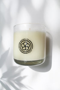 an up close video of a candle - the candle wax is a white color and is inside a clear glass container that doubles as a drinking tumbler once the candle burns out.