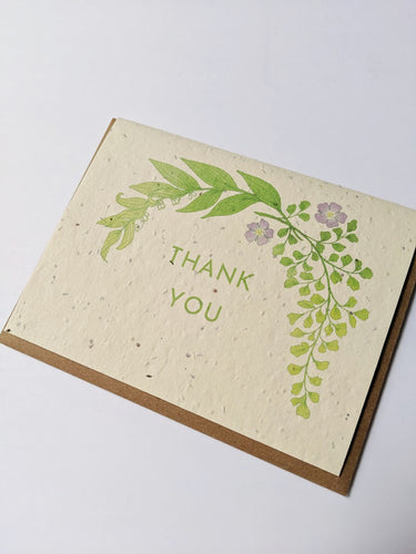 a plantable seed card - the card has a textured look from the seeds imbedded in the paper. There is a leaf drawing with two small purple flowers on this one that says 