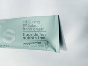 an up close look at the tube of David's Natural Toothpaste. it says "Premium Natural Toothpaste. Whitening, Antiplaque, Fresh Breath, Flouride Free, Sulfate Free. Peppermint essential oil blend"