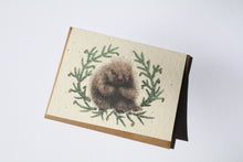 Load image into Gallery viewer, a plantable seed card - the card has a textured look from the seeds imbedded in the paper. There is a drawing of a porcupine surrounded by pine sprigs on this card
