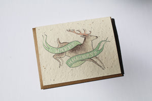 a plantable seed card - the card has a textured look from the seeds imbedded in the paper. There is a deer drawing on this one that says "HAPPY HOLIDAYS" on a green banner going across the deer