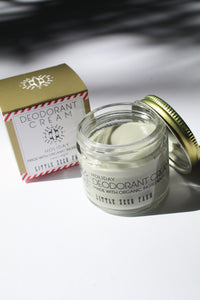 a small jar of cream deodorant. It is in a glass jar with a tin lid. it is next to the box it comes in that says "Deodorant cream - holiday. made with organic ingredients."