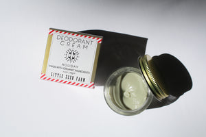 a small jar of cream deodorant. It is in a glass jar with a tin lid. it is next to the box it comes in that says "Deodorant cream - holiday. made with organic ingredients."