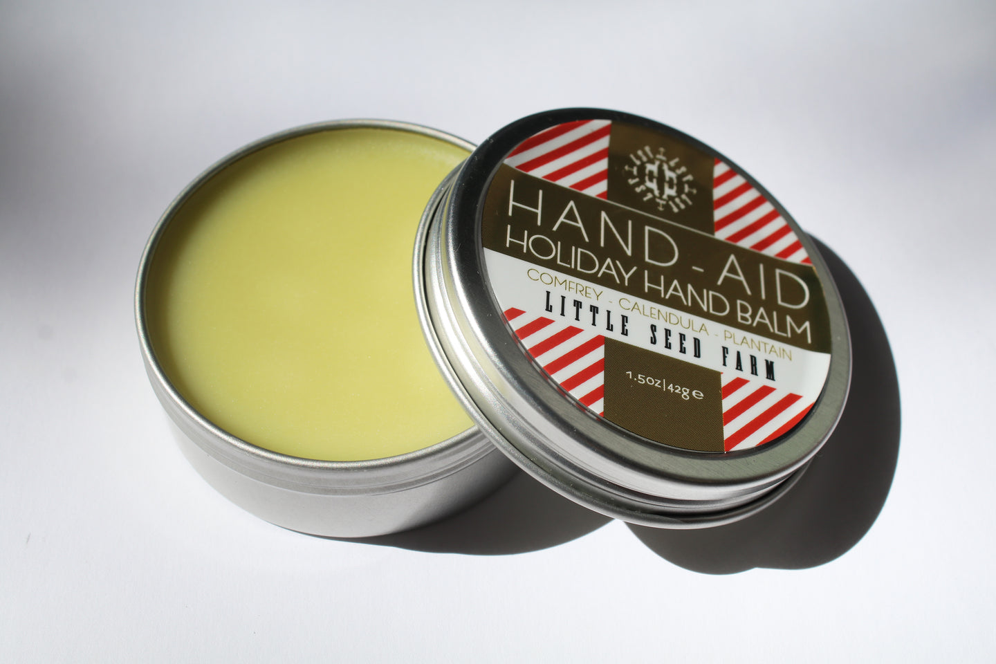 a tin jar of holiday hand balm by Little Seed Farm