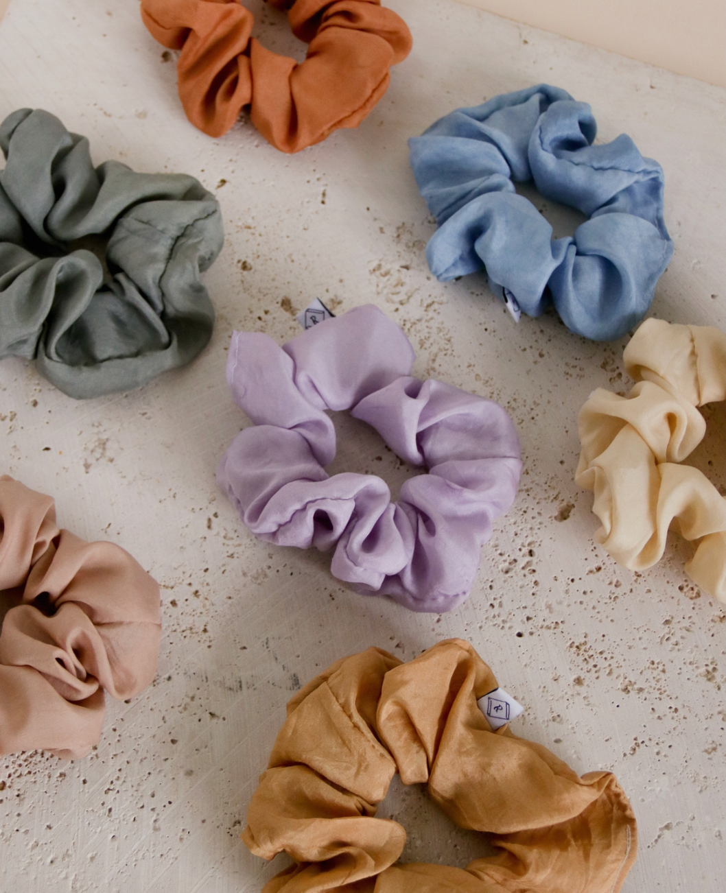 multiple silk scrunchies laying next to each other in varying colors