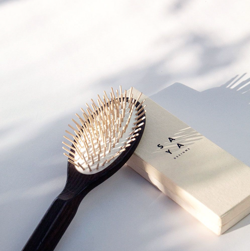 a dark colored wooden hair brush with light wood bristles 