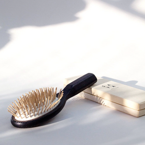 a dark colored wooden hair brush with light wood bristles 