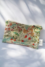 Load image into Gallery viewer, a cream colored cosmetic bag with a gold zipper and summery floral pattern
