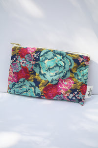 a navy blue colored cosmetic bag with a gold zipper and large floral design