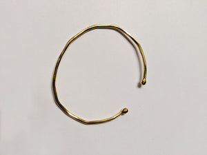 an up close look at a hand hammered brass bracelet. It is adjustable, as it is not a full circle. 