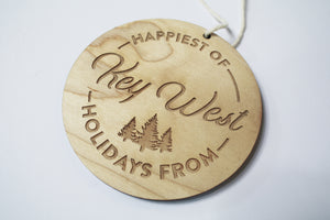 an up close look at a circular wooden ornament that says "Happiest of Holidays from Key West"