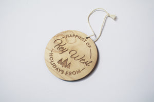 an up close look at a circular wooden ornament that says "Happiest of Holidays from Key West"