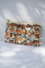 Load image into Gallery viewer, a cream colored cosmetic bag with a gold zipper and orange design
