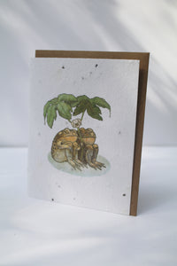 a card with seeds imbedded in the paper to pant and a watercolor drawing of two toads sitting under a leaf